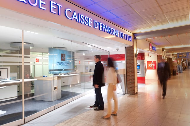 Glasfront einer Bankfiliale in einem Einkaufszentrum mit dem Schriftzug „Banque et Caisse d’Epargne de l’Etat“, davor Personen