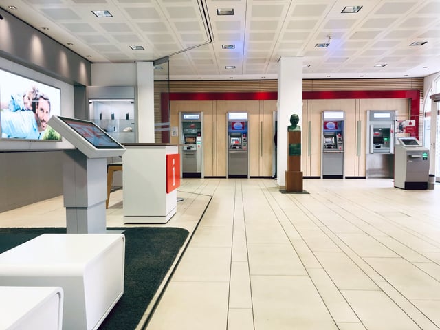 Kundenhalle mit Terminal, Infotheke, Büste und einer Reihe von Geldautomaten
