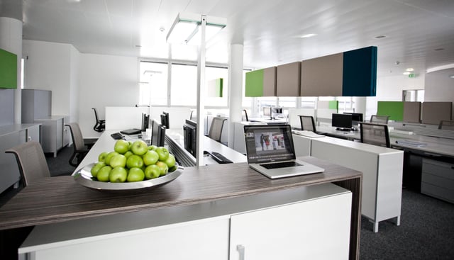 Arbeitsplätze mit Laptop und einer Schale grüner Äpfel auf einem Sideboard