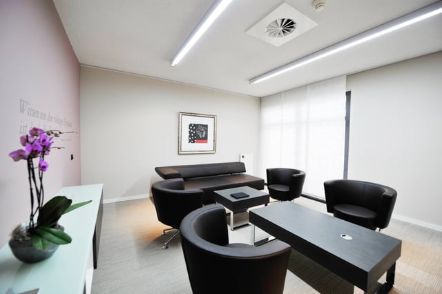 Besprechungsraum mit schwarzen Sesseln, Sofa, Couchtisch und Orchidee