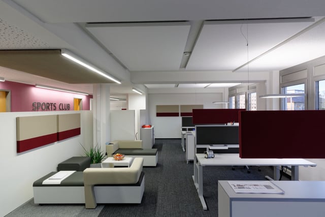 Bürofläche mit Sitzlandschaft, Schreibtischen und dunkelroten Tischtrennwänden, an der Wand der Schriftzug „Sports Club“