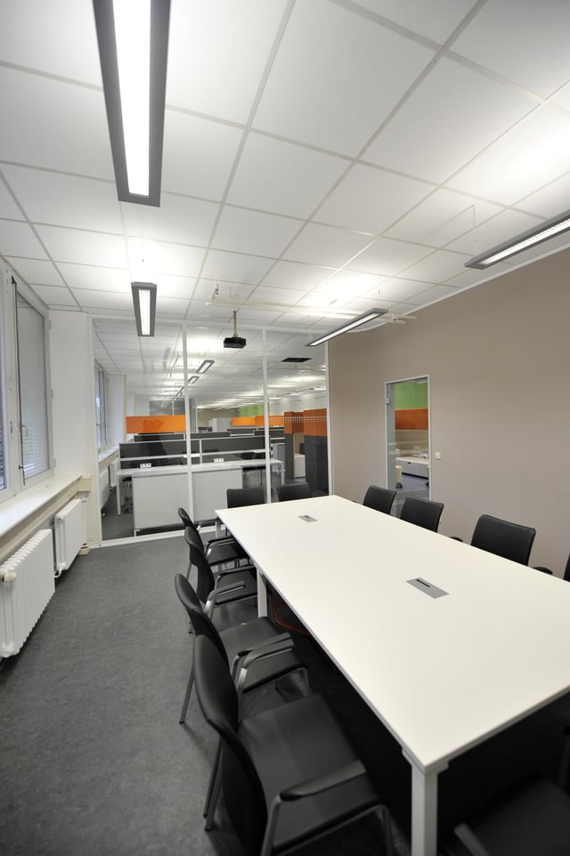 Besprechungsraum mit langem weißem Tisch und schwarzen Stühlen