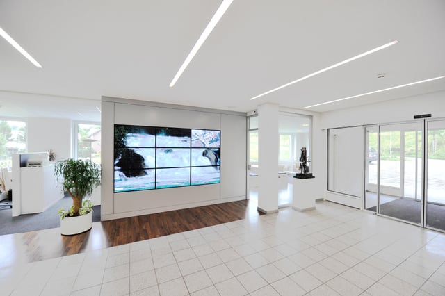 Eingangshalle mit Videowand, Holzboden und Glasschiebetüren