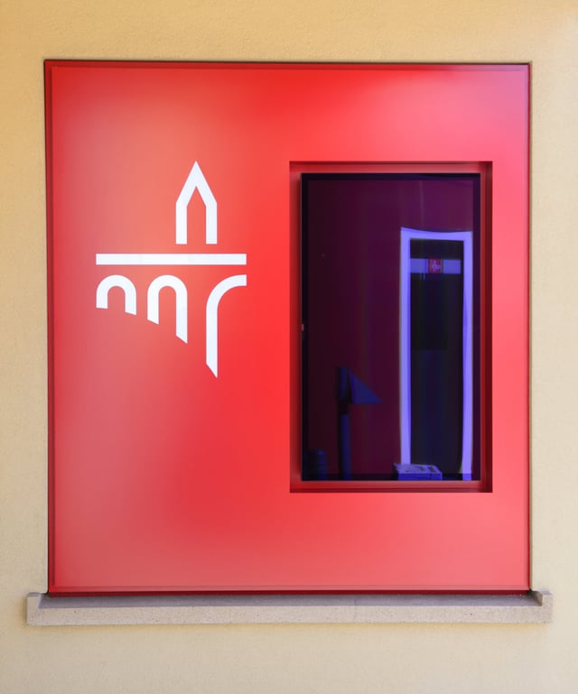 Rote Fassadenverkleidung mit weißem Logo um ein Fenster