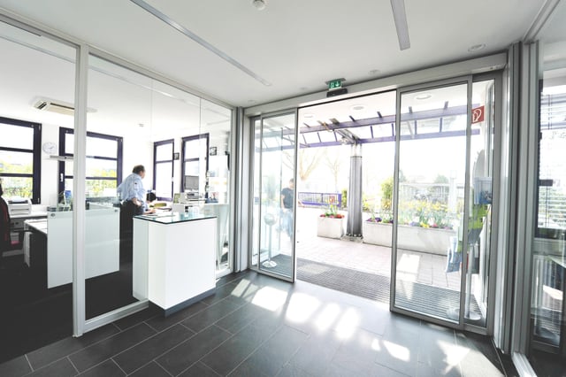 Pforte mit Theke hinter Glas und Blick durch die Schiebetüren nach draußen