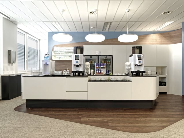 Weiße Kaffeetheke mit zwei Kaffeevollautomaten und Getränkekühlschrank